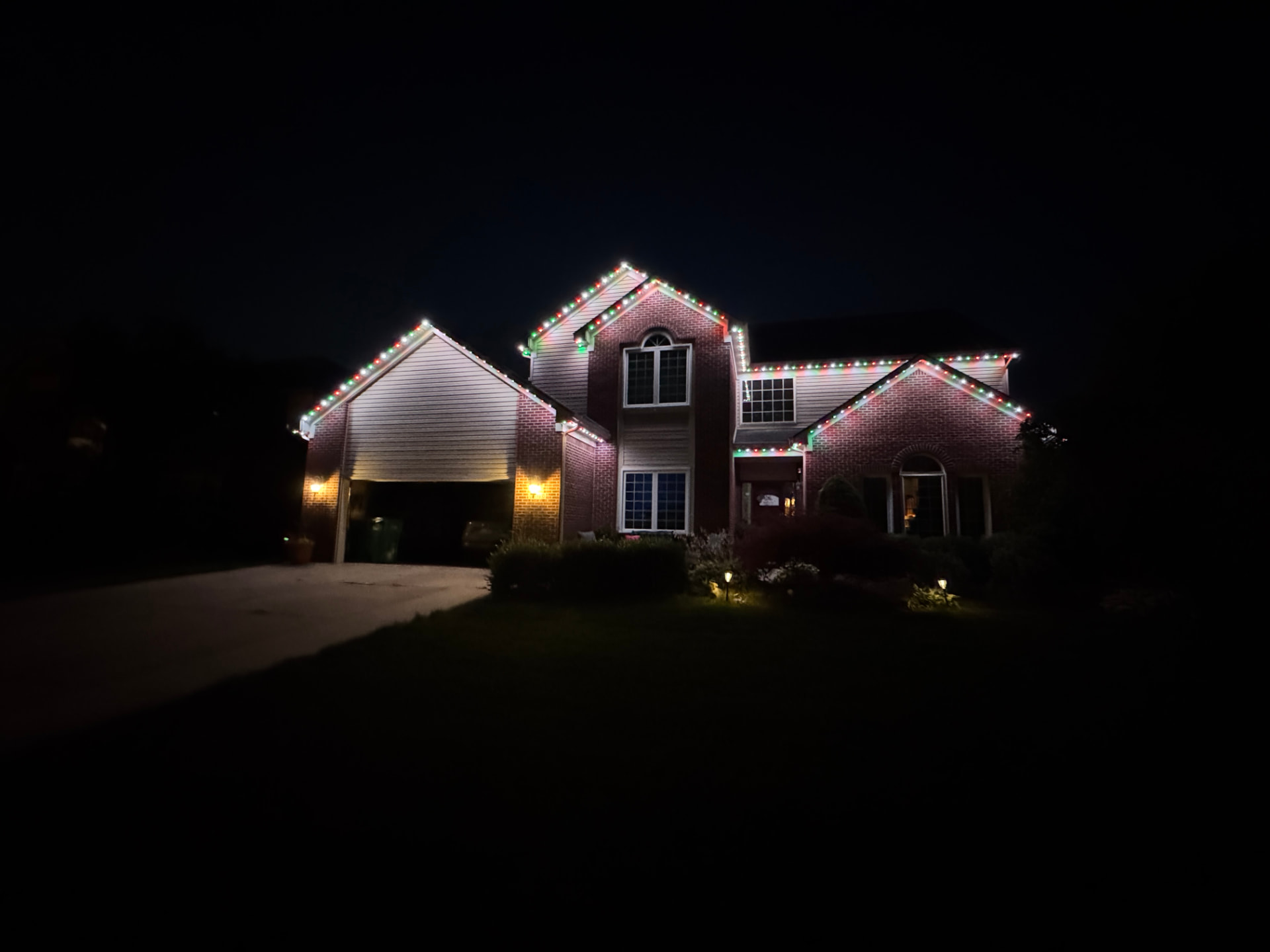Brick home outlined in red, green and white permanent Christmas lighting