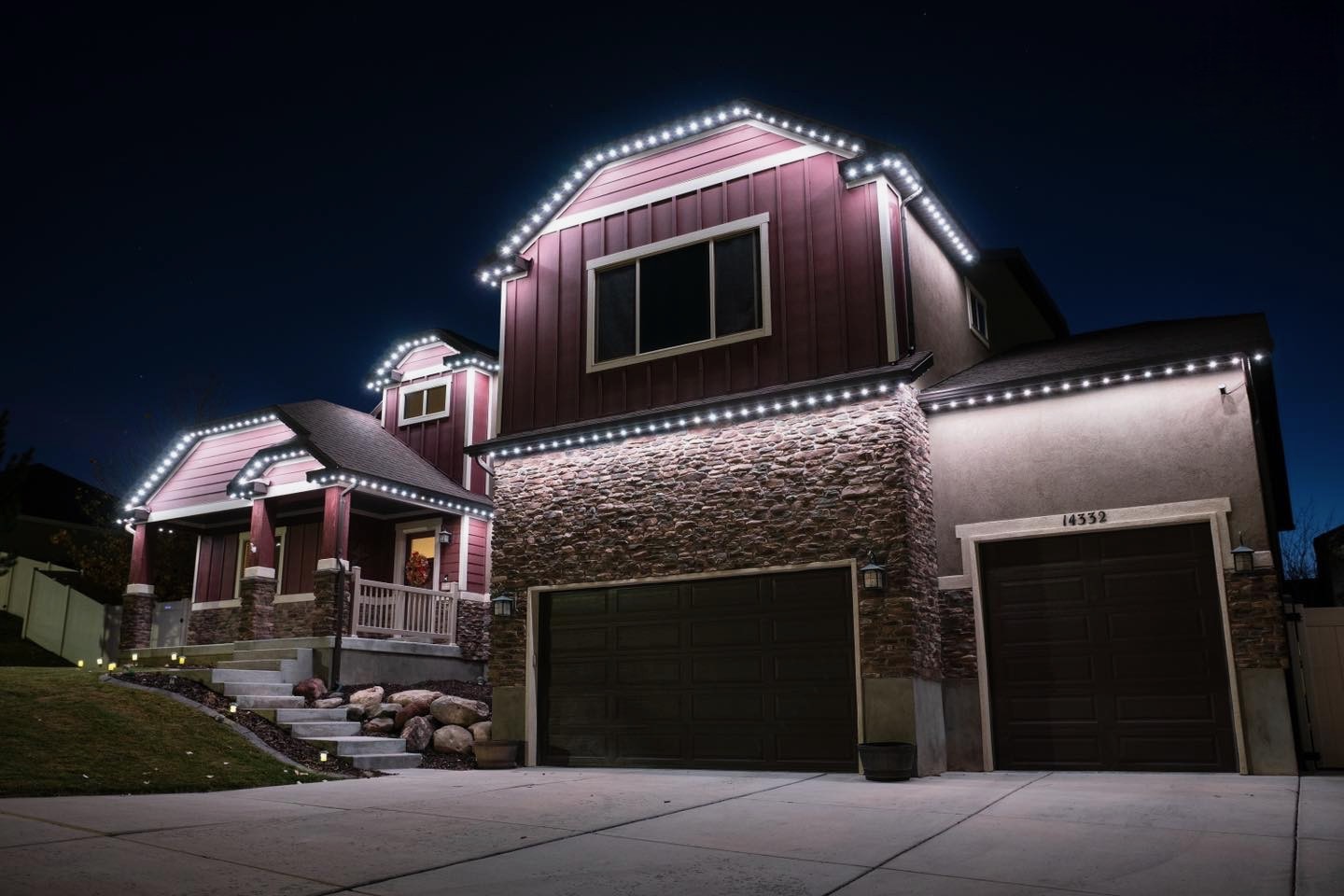 Two-story home outlined in crisp white permanent LED lighting at night